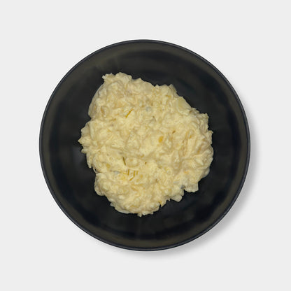Schwarze Schüssel mit Kartoffelsalat mit Mayo auf weißem Hintergrund