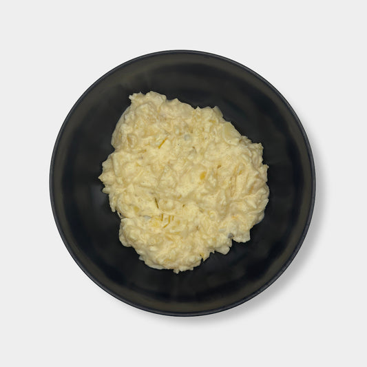 Schwarze Schüssel mit Kartoffelsalat mit Mayo auf weißem Hintergrund