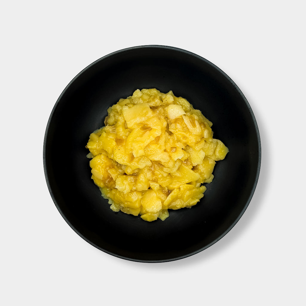 Schwarze Schüssel mit Kartoffelsalat mit Röstzwiebeln auf weißem Hintergrund